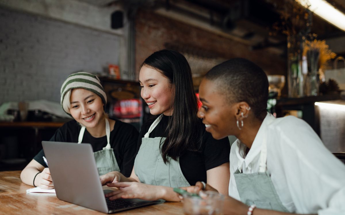 Three cafe team members working together on a laptop